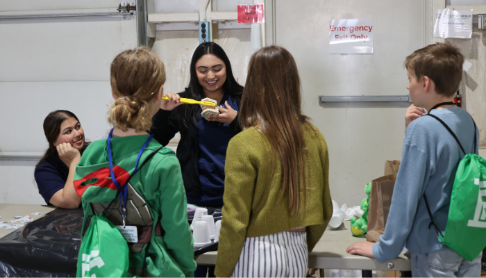 Students participate in a hands-on activity during Career Discovery Day while an Eastland-Fairfield student demonstrates a tool and speaks with middle school visitors gathered around a table.