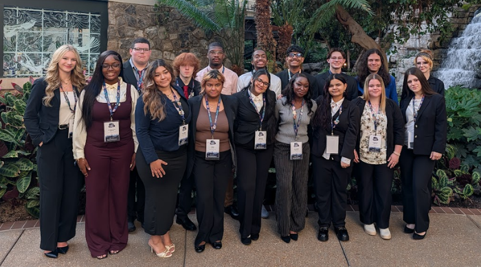 Eastland-Fairfield students pose together in professional attire at the BPA National Leadership Conference in Nashville, standing in front of palm trees, greenery and a waterfall.