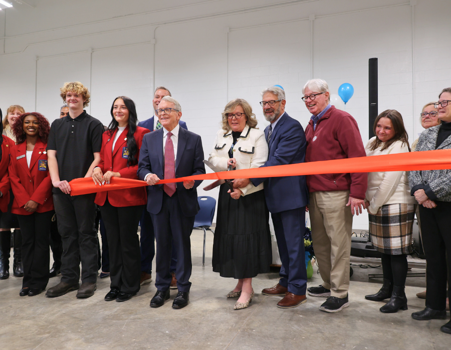 Governor Mike DeWine, Superintendent Shelley Groves, and Eastland-Fairfield leaders cut a large orange ribbon alongside students and staff during the grand opening of the NextGen Training Center.