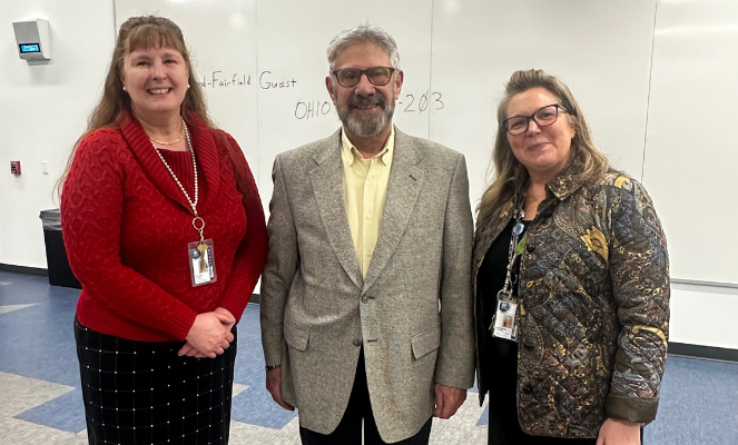 Bill McGowan stands betweenDawn Lemley (Treasurer) and Shelley Groves (Superintendent/CEO), all smiling for a group photo in a classroom setting after his Hall of Fame recognition.