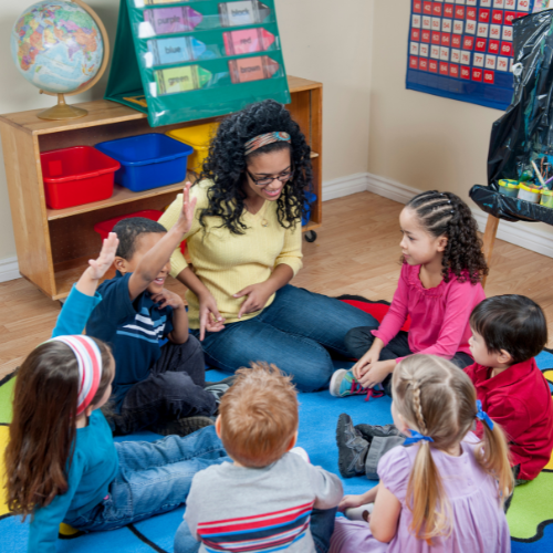 Students and teacher sitting on the floor in a circle