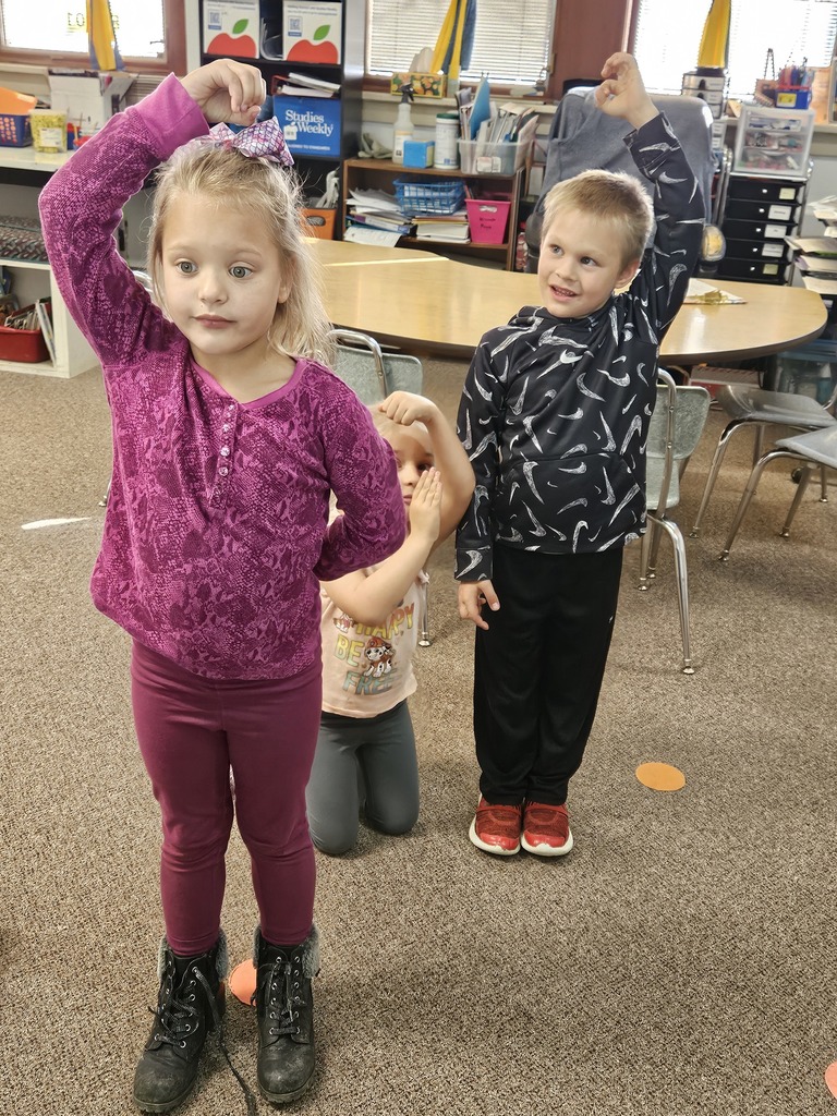 a boy and a girl holding their hand above their head to make a dot for the letter i