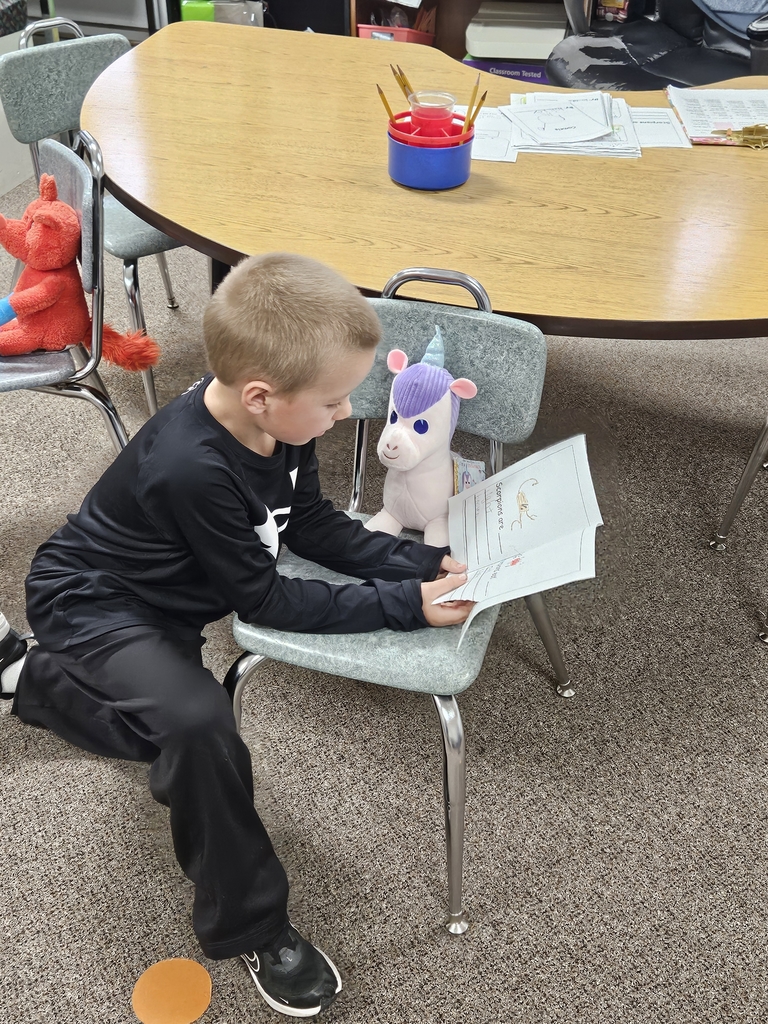 a boy reading to stuffed animal