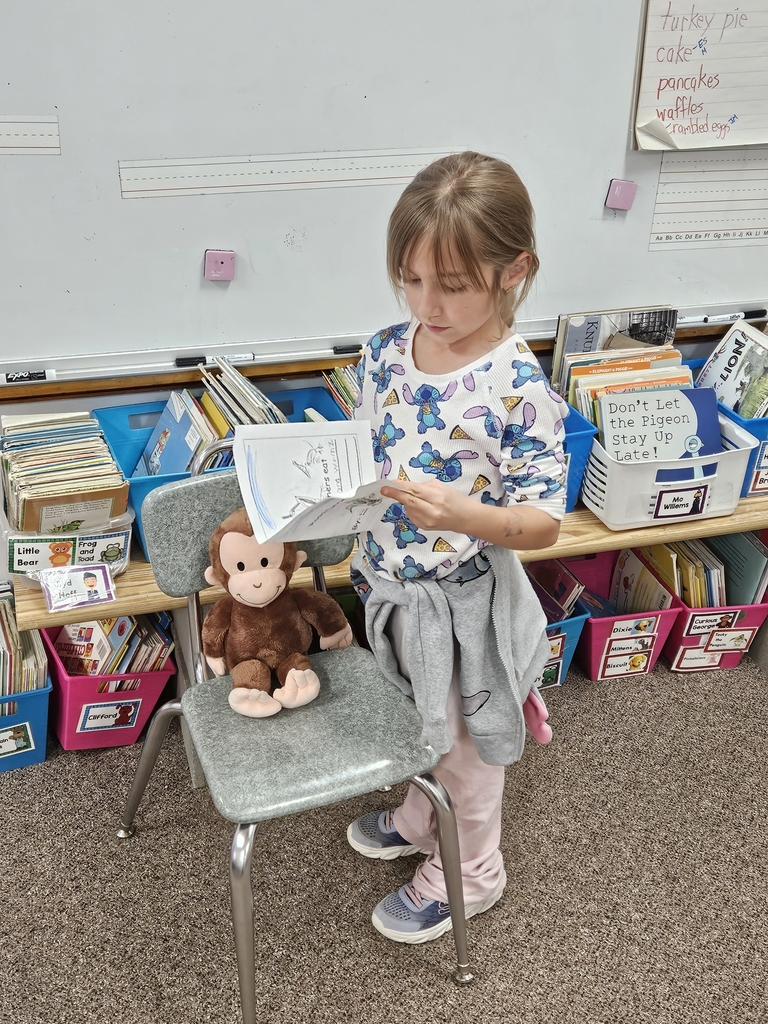 a girl reading to stuffed animal