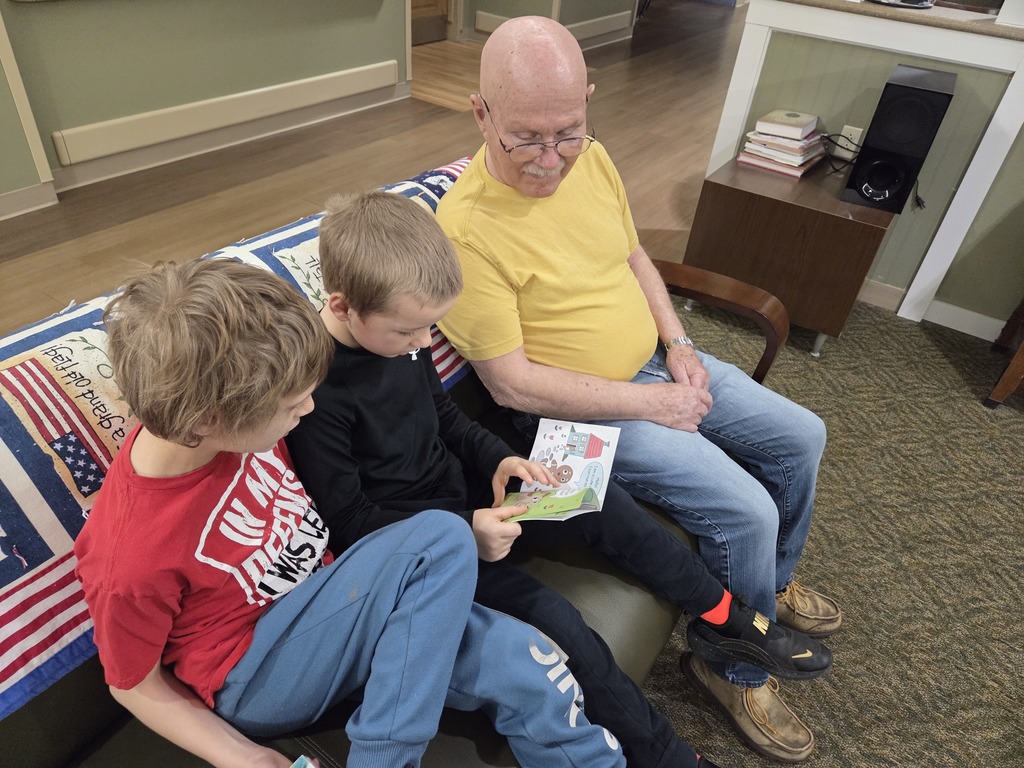 Two boys reading to a man on a couch