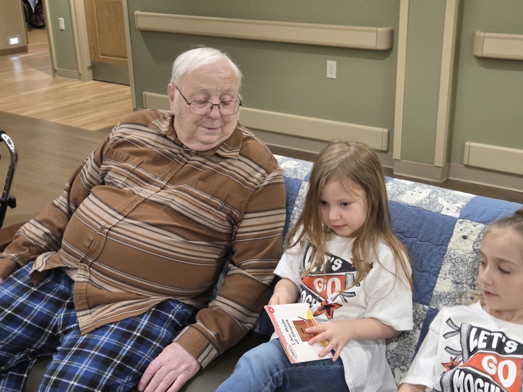 Two girls reading to a man on a couch