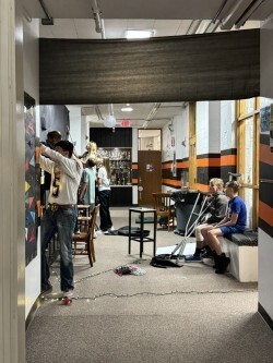 students decorating the walls in a hallway with a black fabric ceiliing