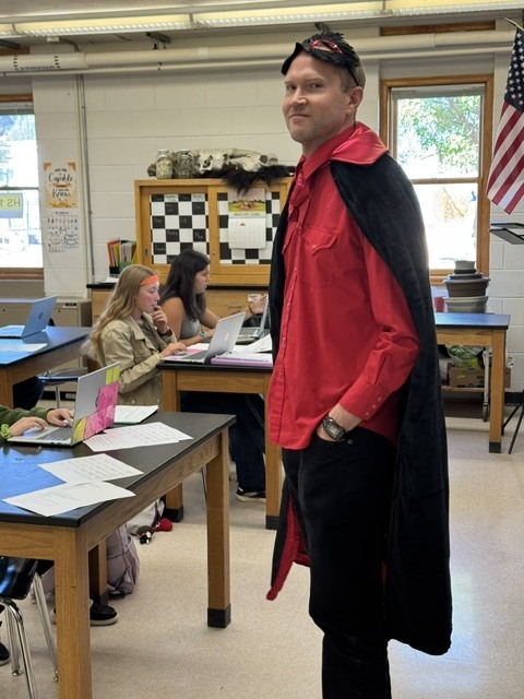 Teacher with a red shirt and black superhero cape