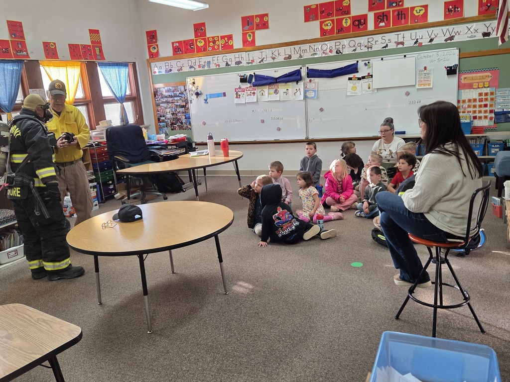 11 kids and 2 adults watching 2 firefighters