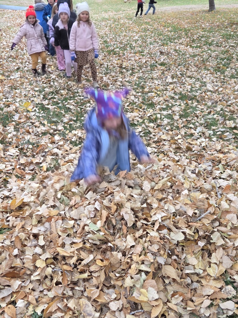 a girl jumping into a pile of leaves 