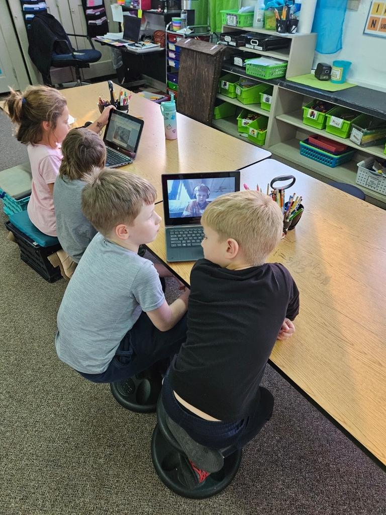 four kids looking at 2 computer screens 