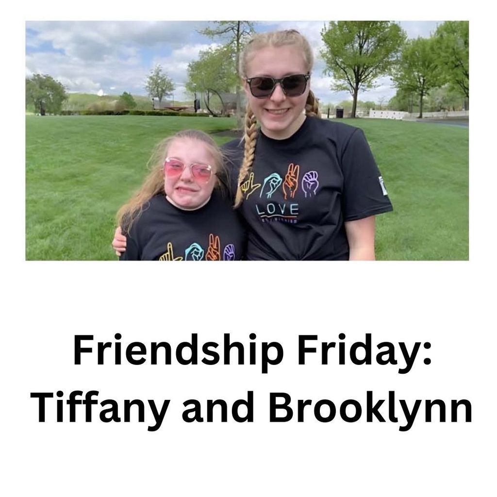 brooklyn and tiffany arms around each other with asl t shirts on standing with a green field and trees behind them. 