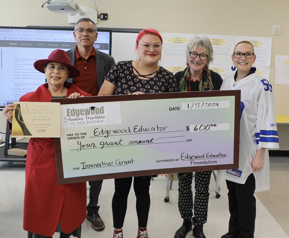 Teachers smiling and holding a large check