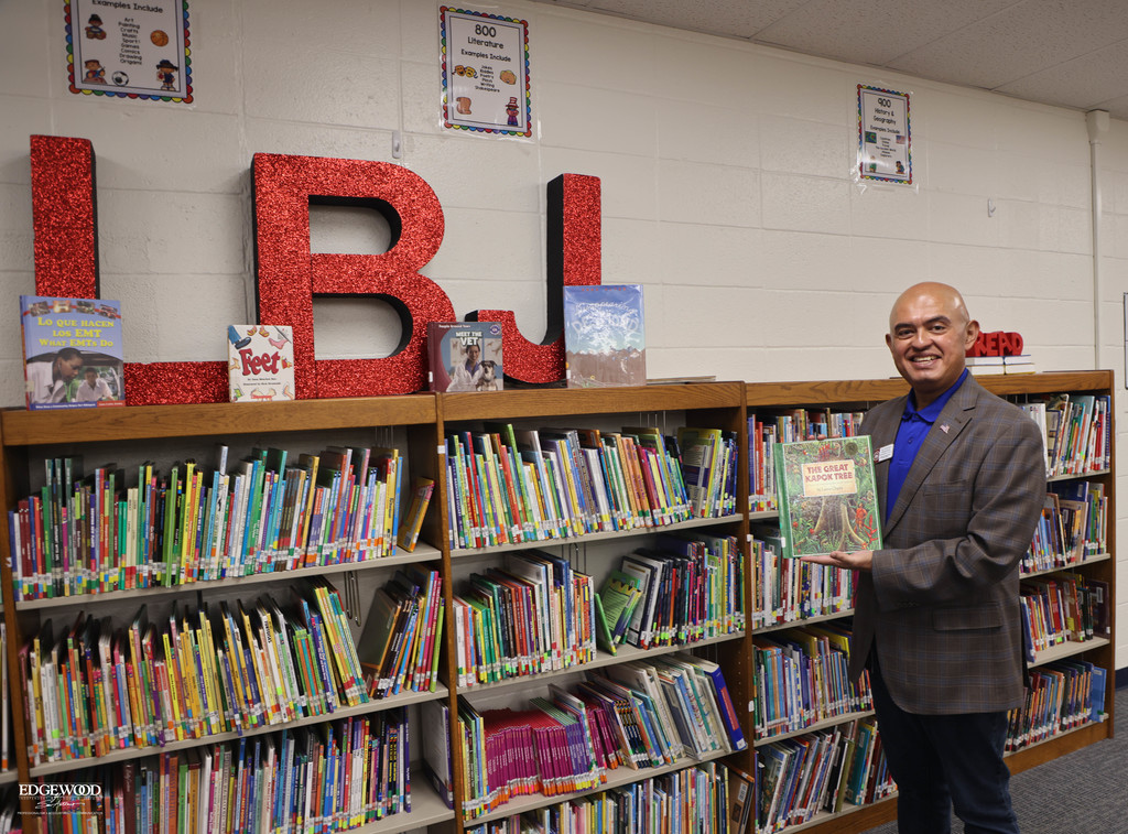Dr. Hernandez poses with a book at LBJ Elementary School