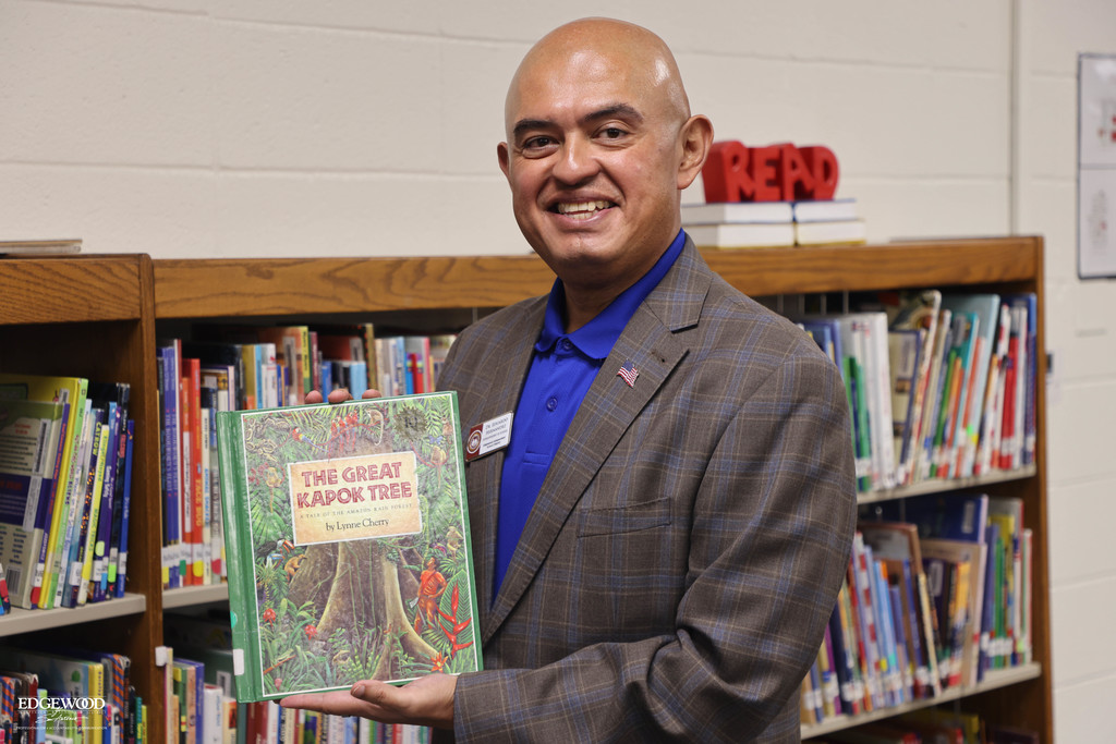 Dr. Hernandez poses with a book at LBJ Elementary School