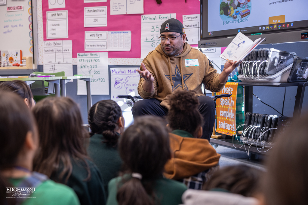A parent volunteer reads to young students at LPLSG