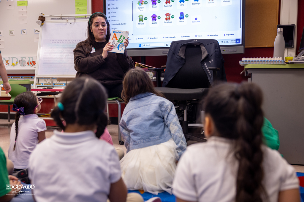 A parent volunteer reads to young students at LPLSG