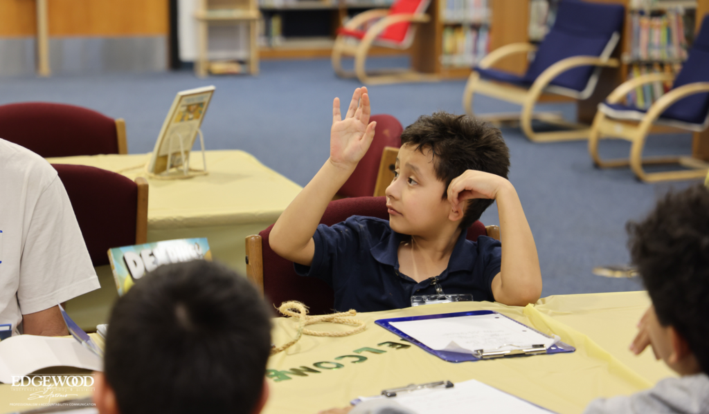 Student raising his hand confidently answering a question.