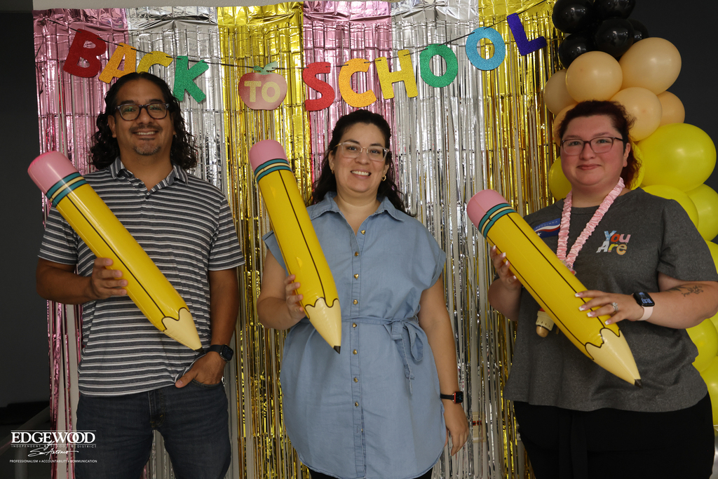 new teachers pose for a photo together infront of a Back to School backdrop