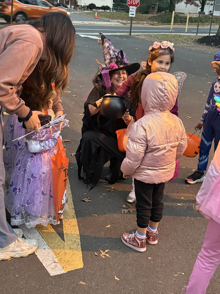 Volunteer handing out candy while children trick or treat