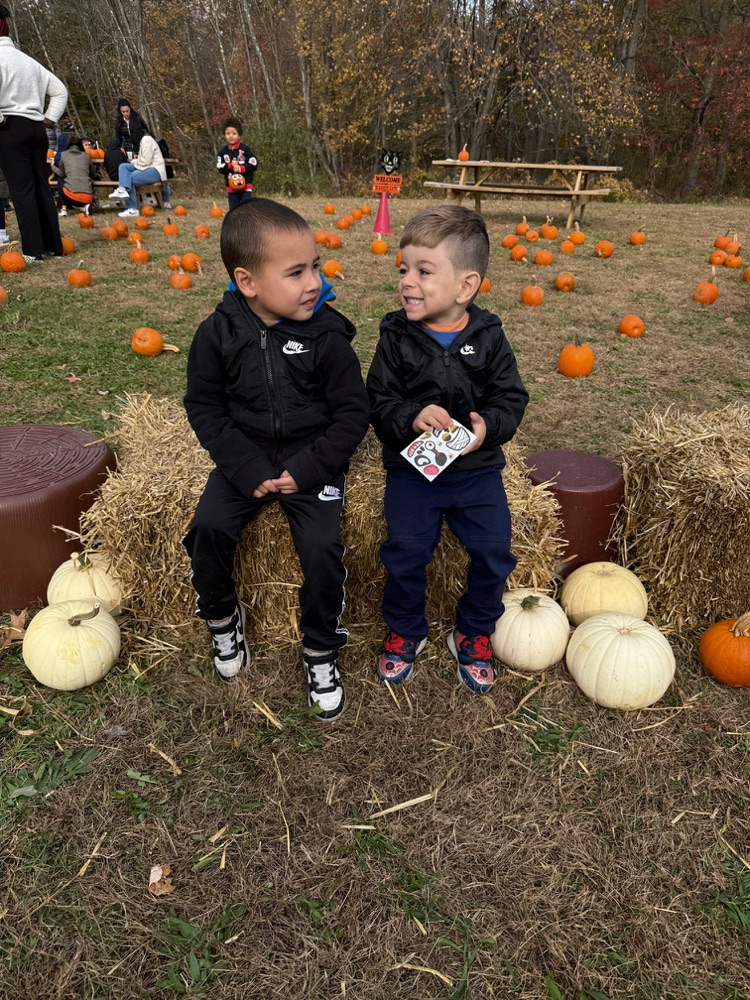 two young boys sitting on a Haybale looking at each other
