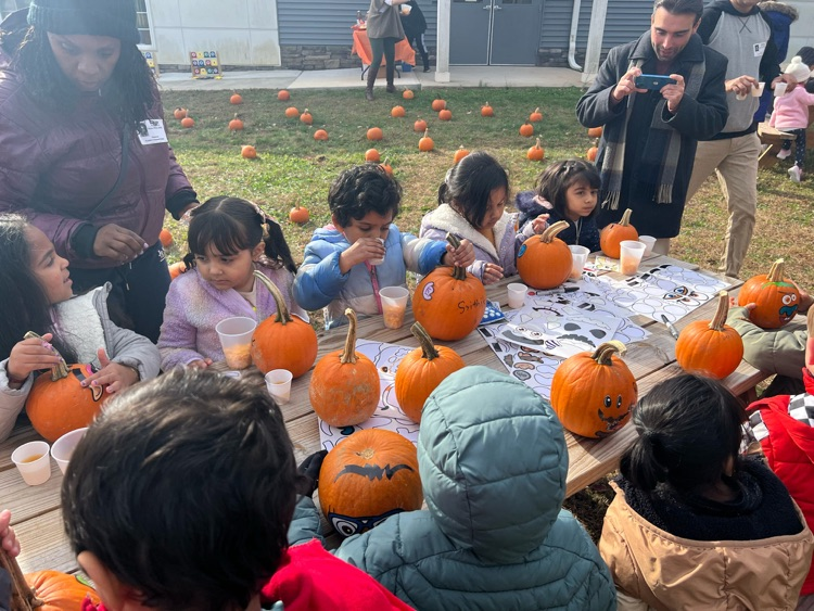 multiple young children sitting at a table with pumpkins