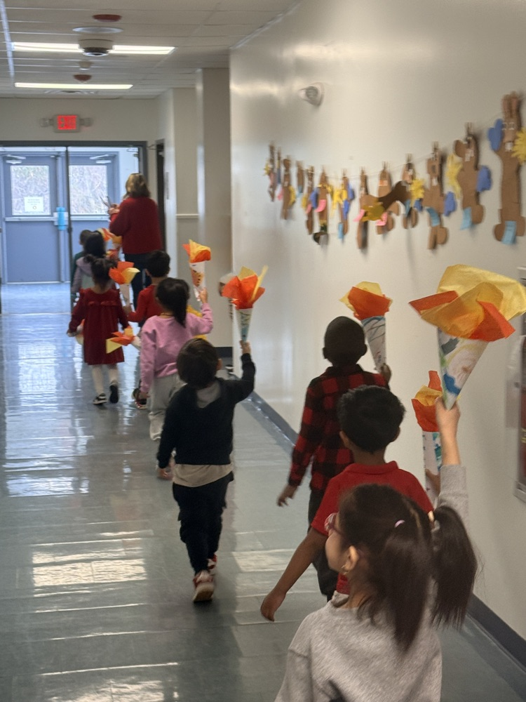preschool children holding up handmade paper torches 