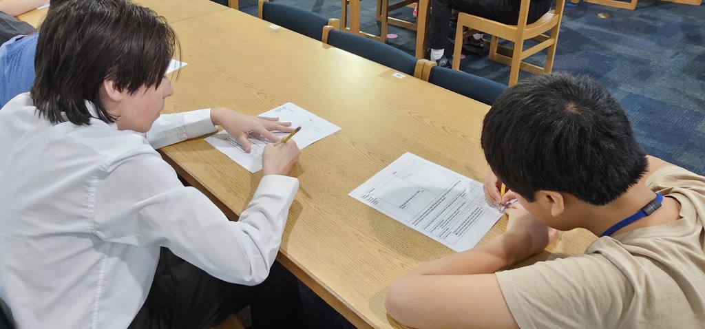 Two male students writing on paper