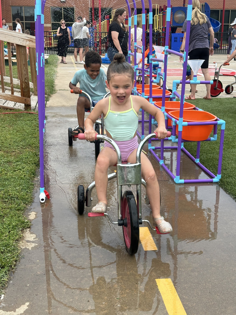 students riding trikes through the car wash