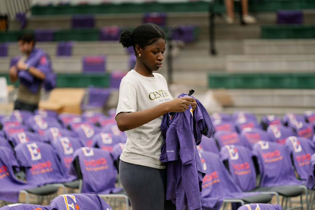 students setting up shirts on chairs in a gym
