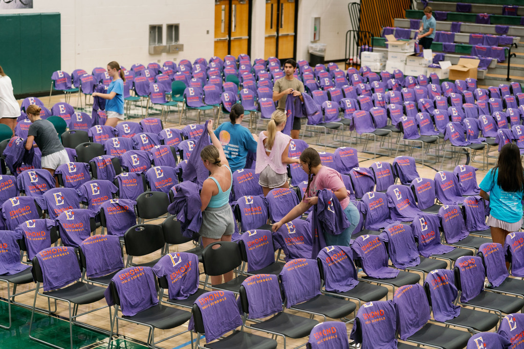 students setting up shirts on chairs in a gym