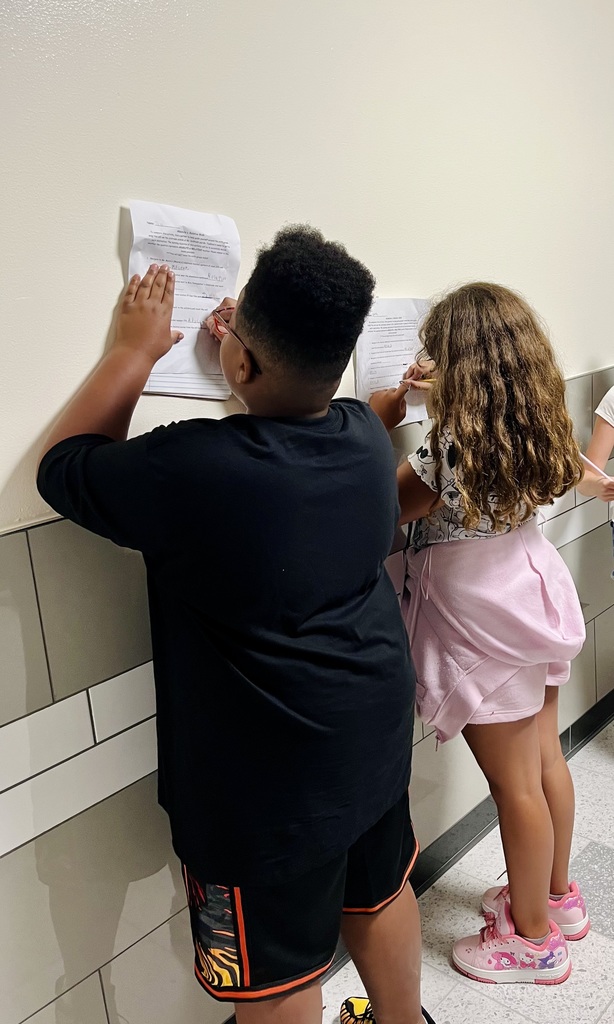 Two students document their answers on a social studies assignment while working as a team.