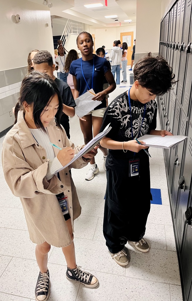 Students stand in hallway while working on an assignment for social studies class.