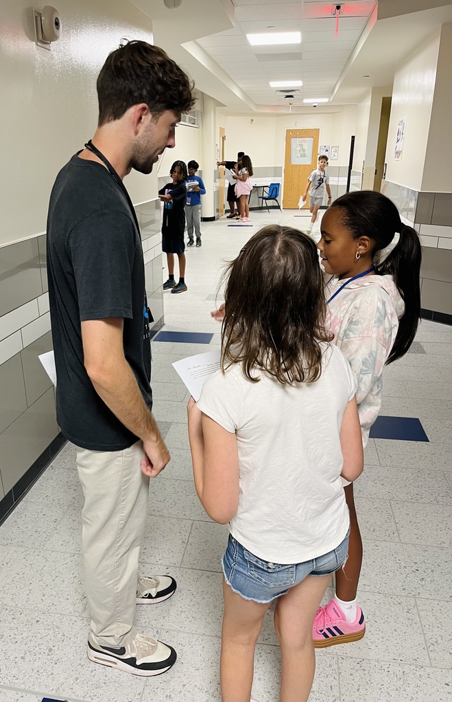 Mr. DeWindt assists students as they work on their social studies assignment in the hallway.
