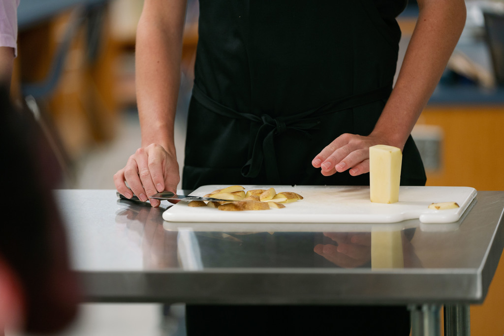 students cutting up a potato during class