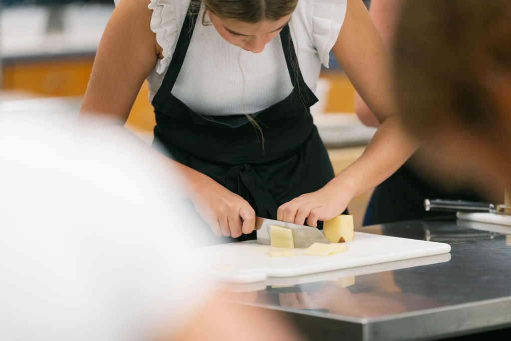 students cutting up a potato during class