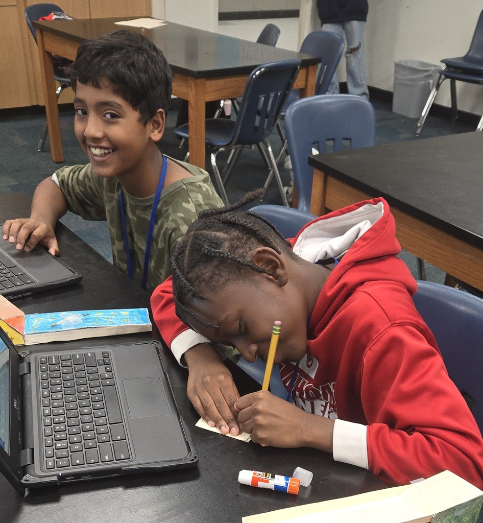 Two students sit next to each other while designer their skimmers for engineering class. 