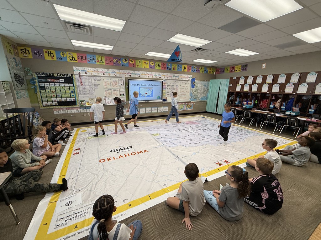 Students walking on and learning about a giant map of Oklahoma
