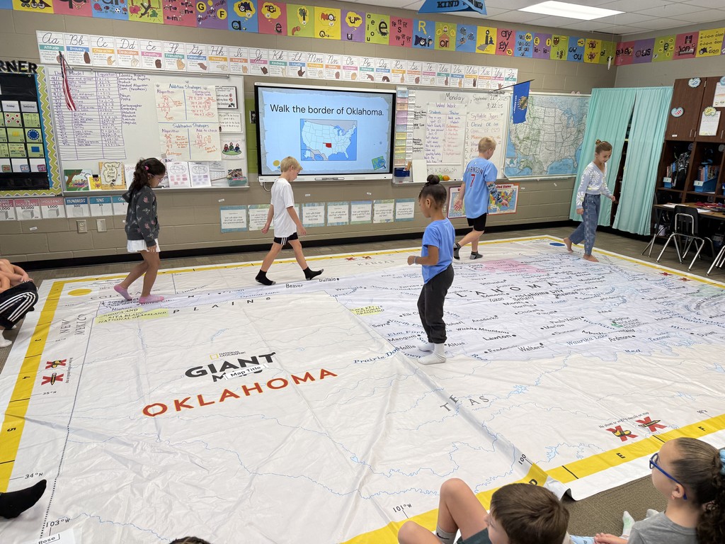 Students walking on and learning about a giant map of Oklahoma