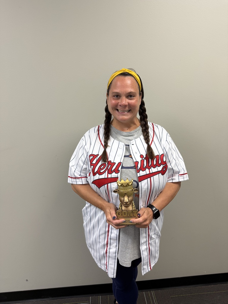 Woman in jersey and braids stands with trophy