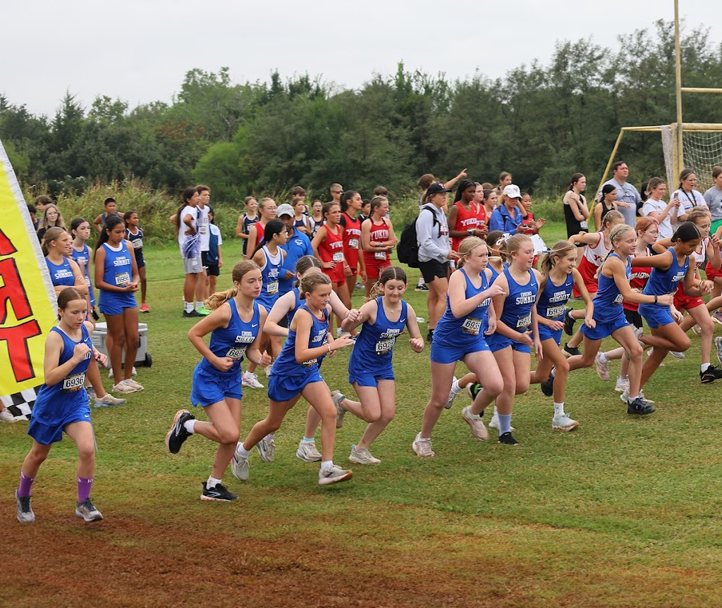 7th grade girls cross country athletes take off from the starting line at a meet.