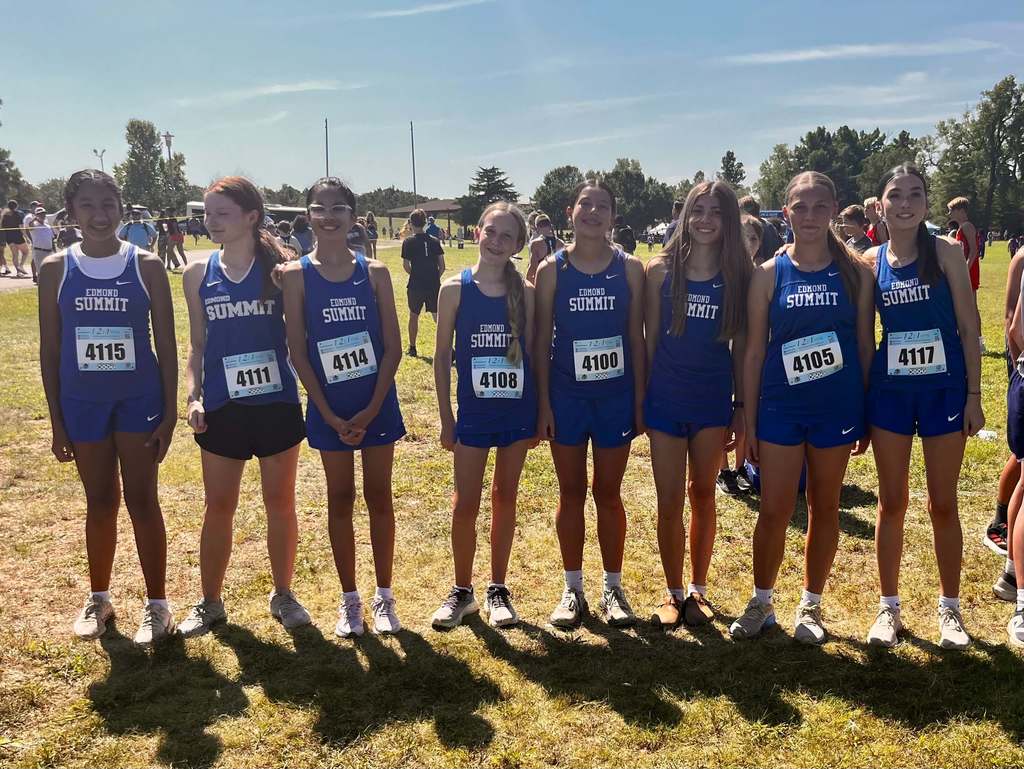 8th grade girls cross country athletes pictured standing together and smiling.