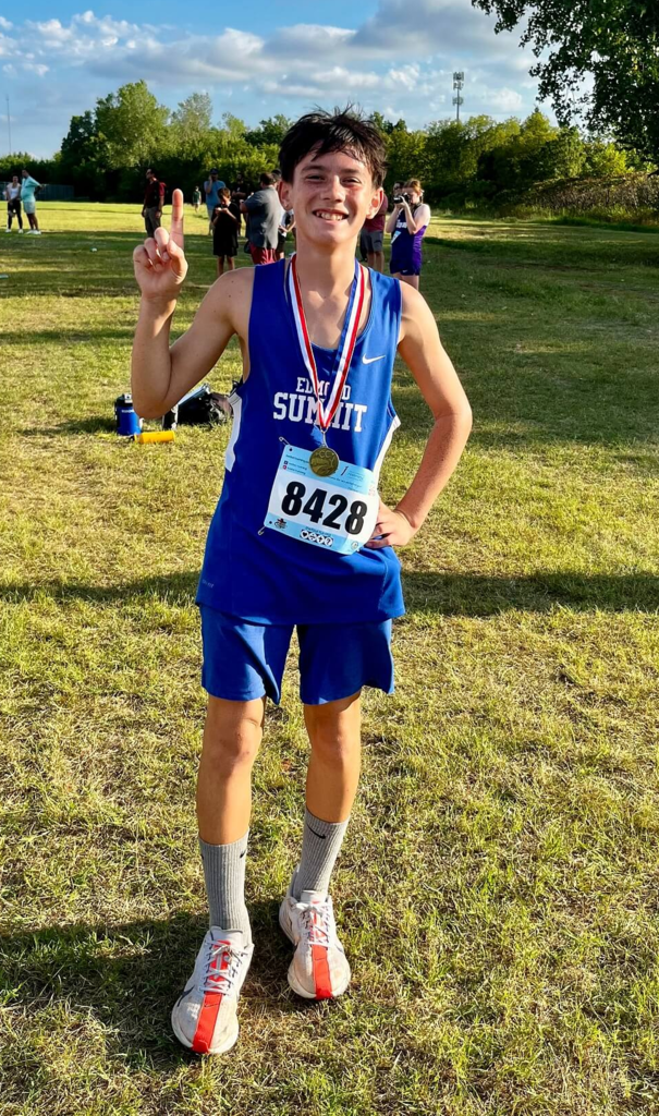 Edmond City Champion, Emmerson C., holds up a #1 using his right hand and proudly wears his 1st place metal.