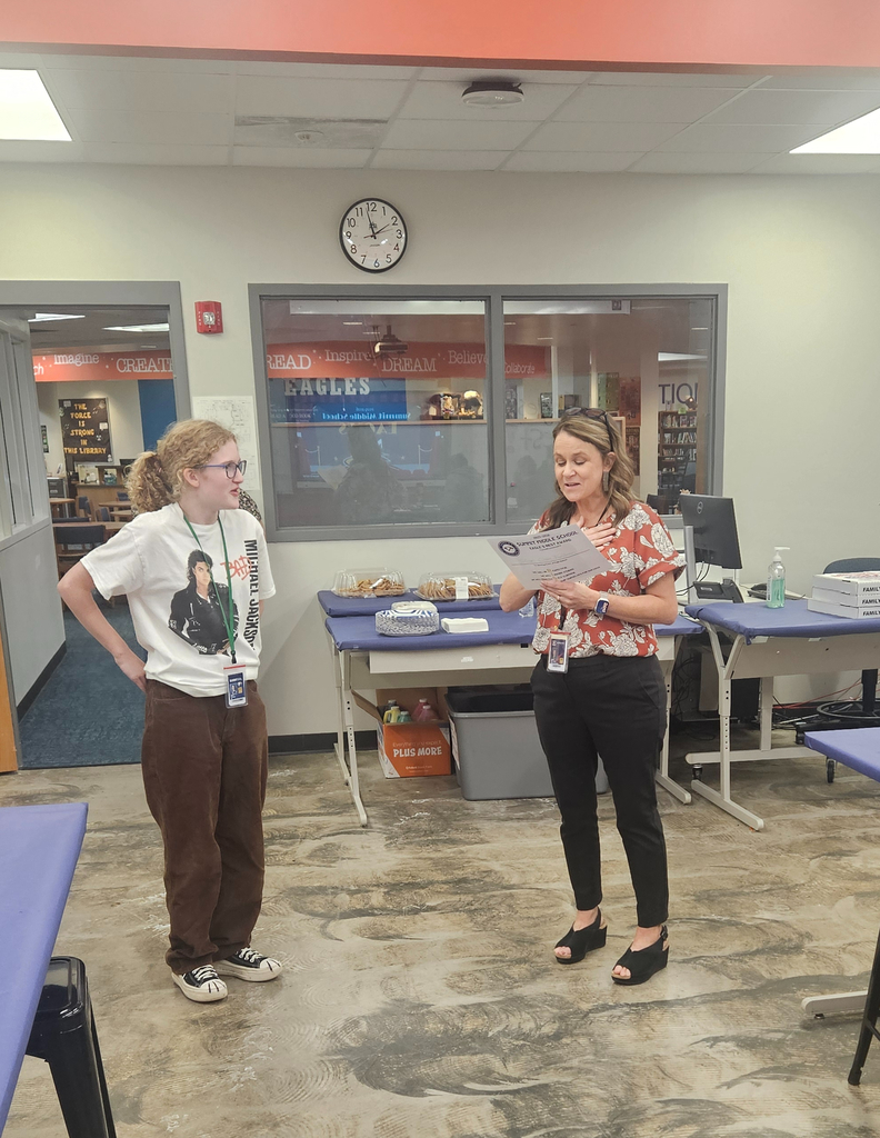 Mrs. Williams reads an Eagle's Nest award to an 8th grade student.