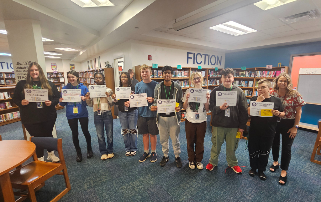 8th grade Eagles Nest recipients stand together smiling and holding their awards. 