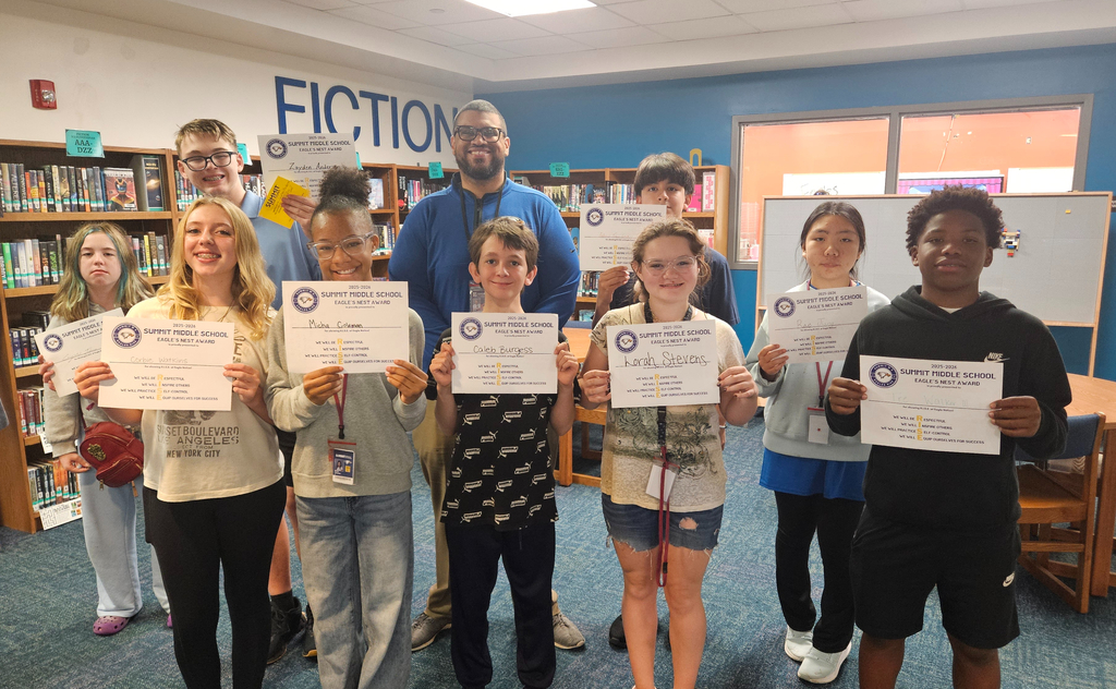 7th grade Eagles Nest recipients stand together smiling and holding their awards. 