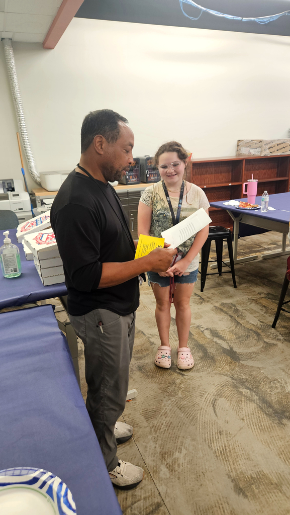 Mr. Lee reads an Eagle's Nest award to an 8th grade student.