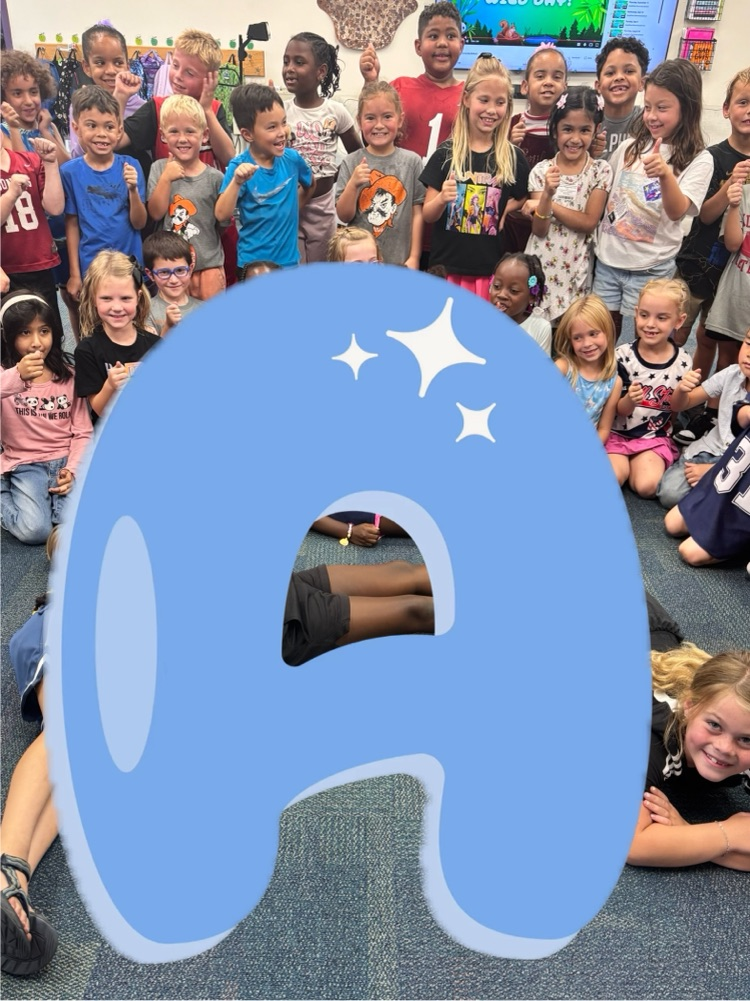 first grade students making the letter a with a letter a graphic covering their bodies 