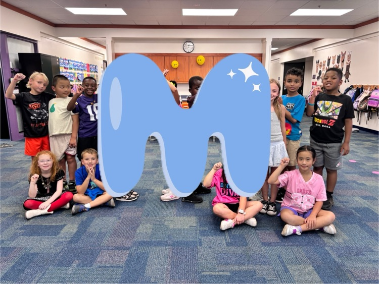second grade students making the letter m with a letter m graphic covering their bodies 