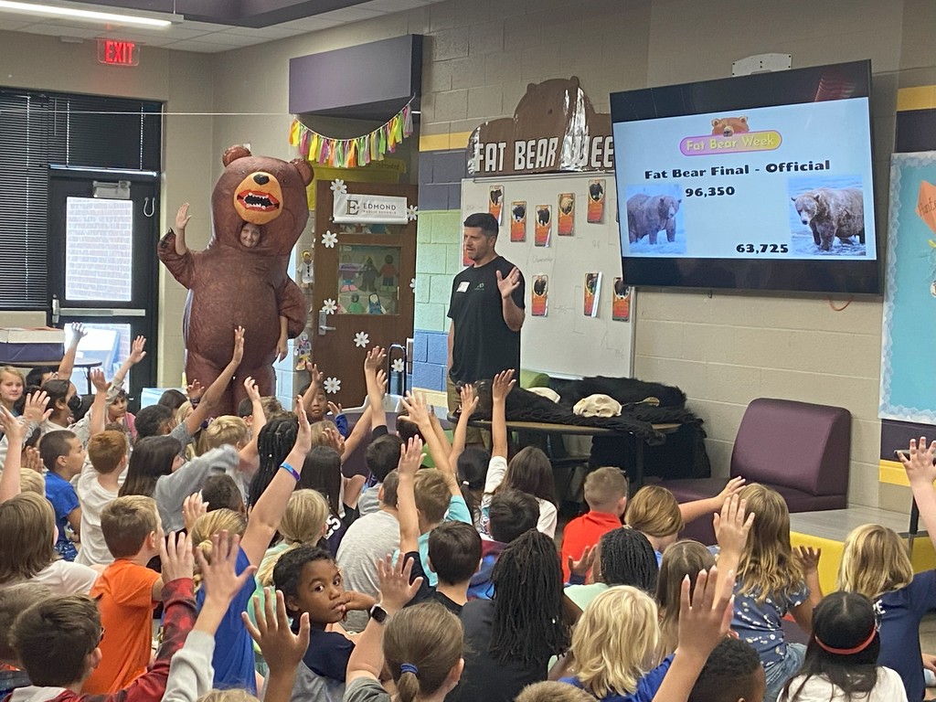guest speaker with students raising hands and teacher in inflatable bear costume